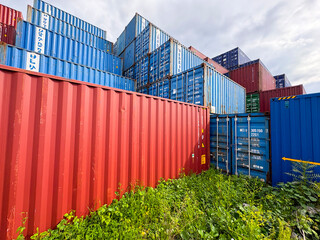Fototapeta premium Stacked blue and red industrial shipping containers in a freight terminal.