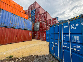 Fototapeta premium Stacked blue and red industrial shipping containers in a freight terminal.