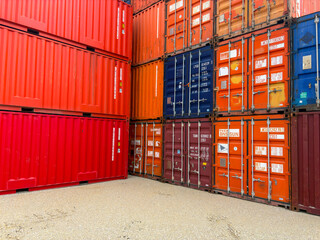 Fototapeta premium Stacked blue and red industrial shipping containers in a freight terminal.