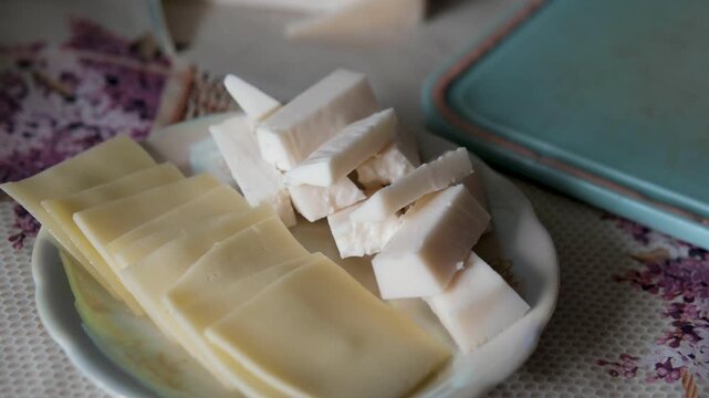 A festive cheese assortment is being sliced and arranged for a holiday table. Close-up of white, sheep, and goat cheeses being cut and served, highlighting texture, freshness, and simple elegant.