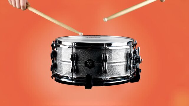 A high-quality 3D render or photo of a professional chrome snare drum with wooden drumsticks poised above it. This clean musical asset is perfect for education, rhythm tutorials, music production bran