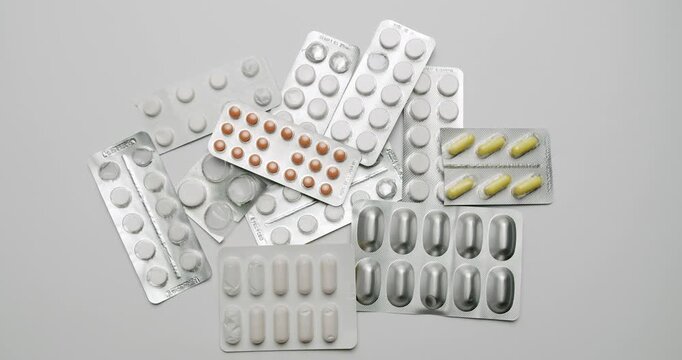 Multicolored pharmaceutical pills and capsules in silver blister packs scattered on an isolated white surface, Various pharmaceutical pills and capsules in blister packs lying on a white background