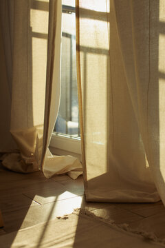 Sunlight streaming through beige linen curtains in a cozy room at golden hour.