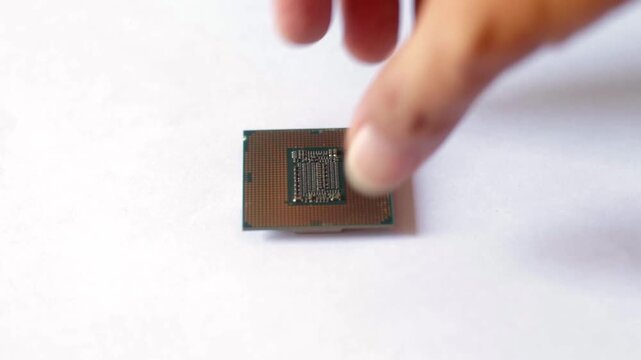 Close up of a hand holding a modern computer CPU processor chip against a white background. Concept for hardware technology, PC building, and digital processing.