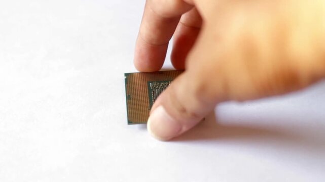 Close up of a hand holding a modern computer CPU processor chip against a white background. Concept for hardware technology, PC building, and digital processing.