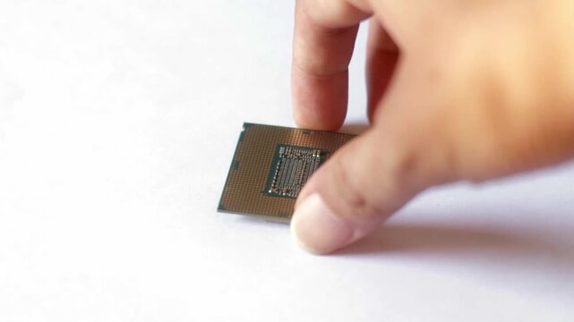 Close up of a hand holding a modern computer CPU processor chip against a white background. Concept for hardware technology, PC building, and digital processing.