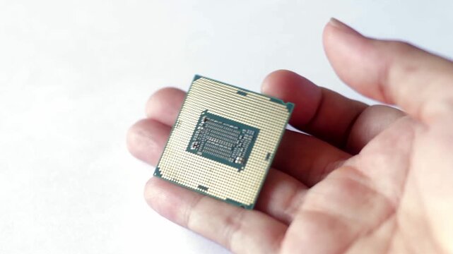 Close up of a hand holding a modern computer CPU processor chip against a white background. Concept for hardware technology, PC building, and digital processing.