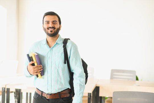 Indian student smiling carrying books at university