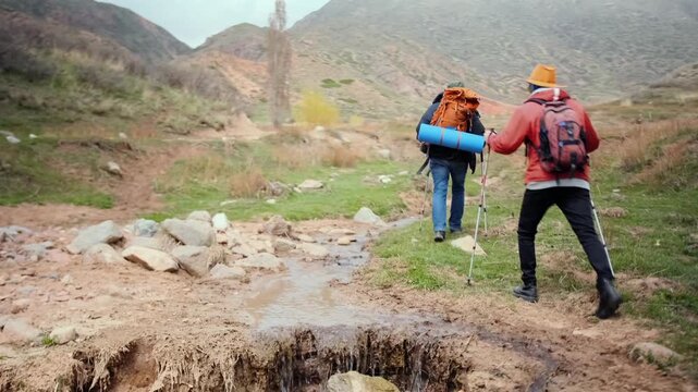two hikers walking forward after crossing rough terrain and ravine, showing persistence, recovery and determination to continue journey through challenging natural landscape