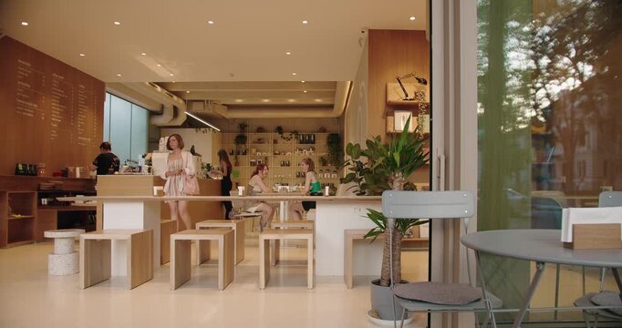 A spacious, modern coffee shop captured in a serene moment with natural lighting. The scene includes a few customers and a barista, detailed with stylish furniture and a cozy ambiance.