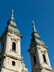 Fototapeta premium Two historic church towers with clocks and crosses under clear sky. Concept of religion, architecture and cultural heritage