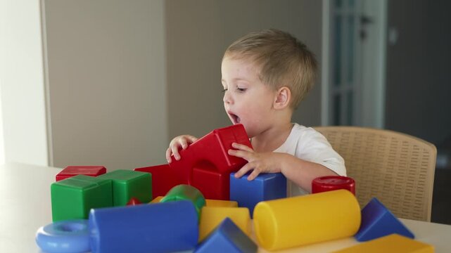 Child stacks colorful block on table while toddler boy plays with toy block indoor learning and concentration using bright shape for creative play and focused concentration during block play