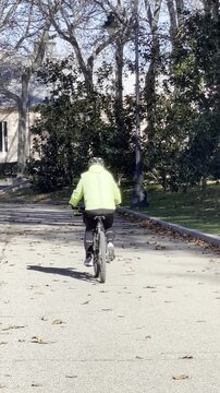 Bicicleta y ciclista pedaleando con casco al aire libre por parque entre &aacute;rboles