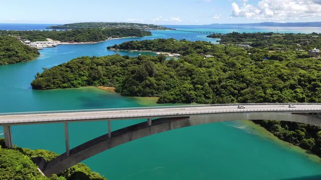 Side tracking aerial view of Warumi Bridge over turquoise sea in Okinawa Japan