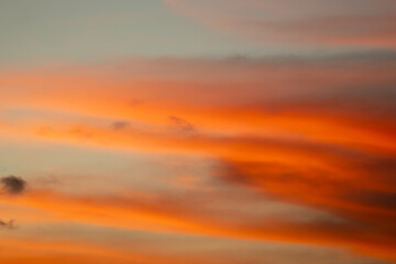 Fototapeta premium Vibrant orange sunset sky with dramatic cloud formations and a smooth gradient background.