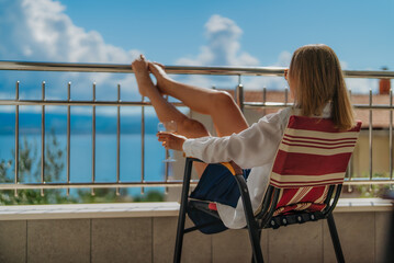 Obraz premium Woman relaxes on terrace overlooking the sea.