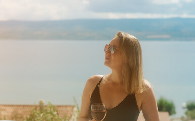 Obraz premium Woman enjoys rose wine on seaside balcony.