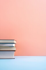 Fototapeta premium Stacked books resting on pastel tabletop with soft backdrop