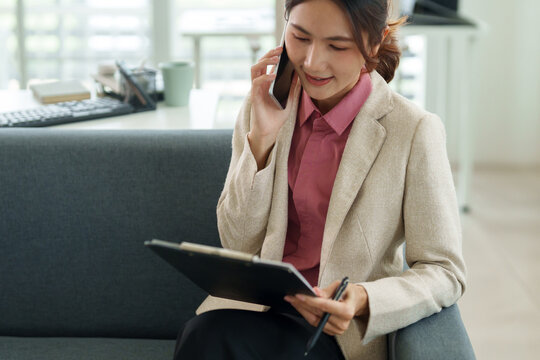 Asian adult businesswoman phone call client discussion professional documents strategy planning modern office environment remote work consultant advisor