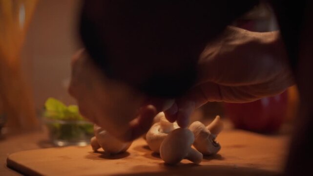 A cook carefully arranges fresh porcini-like champignon mushrooms on a table, ready for marinating or stewing, prior to cutting with a knife for a culinary dish