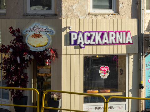Szklarska Poreba, Poland - December 18, 2025: Rozana Paczkarnia bakery facade with an illuminated brand sign, delicious donuts, and winter holiday decorations