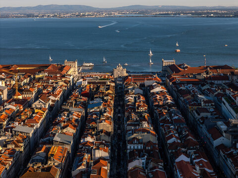 Aerial view of Rua Augusta Arch and Praca do Comercio leading to the Tagus River with sailboats and red-roofed buildings in Lisbon, Lisbon, Portugal.