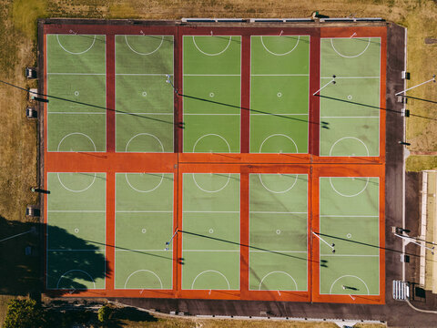 Aerial view of multiple green netball courts with red borders and white markings under bright sunlight in Devonport, Tasmania, Australia.