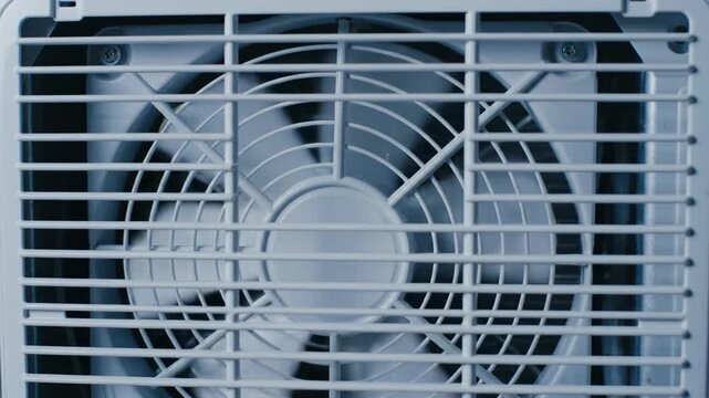 Close-up of a white fan grill with visible blades inside.