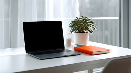 Fototapeta premium Clean white desk with laptop, orange notebook, potted plant and candle by bright window creating calm workspace atmosphere