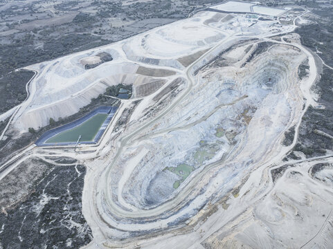 Aerial view of a large open-pit mine with terraced excavation sites and industrial water ponds in Santa Lucia de Gordon, Castile and Leon, Spain.