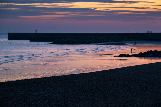 Silhouetted figures on Sussex coast at sundown
