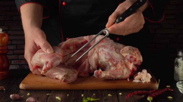 A chef in a black apron uses a fork to probe raw rabbit on a wooden cutting board, surrounded by spices, garlic, and kitchen utensils, creating a vibrant culinary scene in a kitchen environment