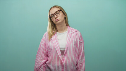 Obraz premium Woman wearing glasses tilts head back with closed eyes in a studio wearing pink striped blouse and white tee; fatigue contemplation.