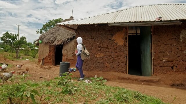 A young girl walks alone to school in a rural African village. The scene highlights independence, responsibility, and the effort required to access education in areas facing water scarcity and limited