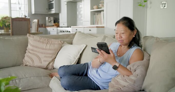 Watch-wearing hands are opening folding phone, tapping screen and aligning card for payment on sofa
