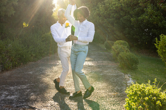 African American male pair dancing on sunlit paved garden path with yellow boutonniere dress shoes