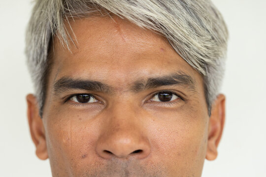 Mature African male facing camera, showing textured skin and faint scar against studio backdrop