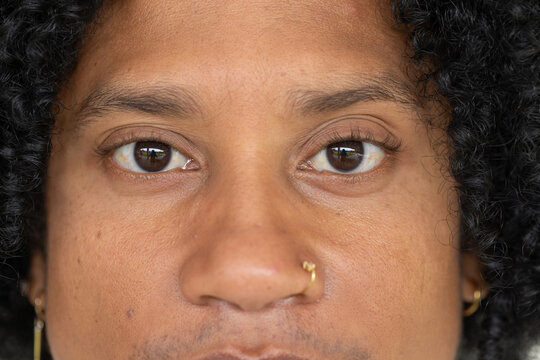 Mid-adult African American man staring at camera in studio, showing gold nose ring and hoop earring