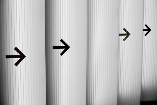 Black directional arrows on ribbed white wall