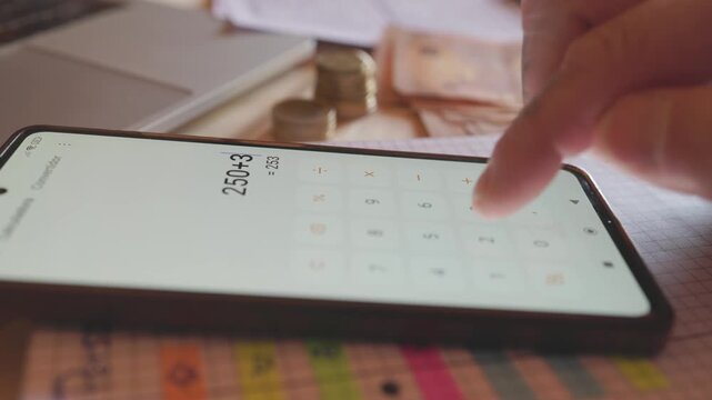 Person calculating home finances on smartphone calculator