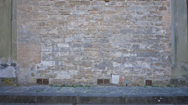 Sharp brick and stone wall texture with weathered mortar and pavement foreground on a street facade; background backplate copyspace calm.
