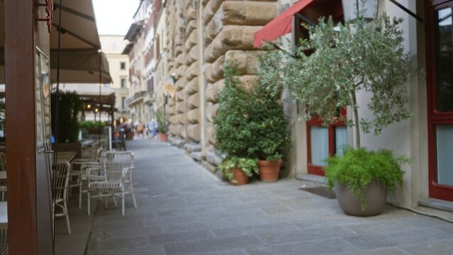 Narrow cafe street scene with soft defocused shallow bokeh and rusticated stone facade; background backdrop copyspace calm.