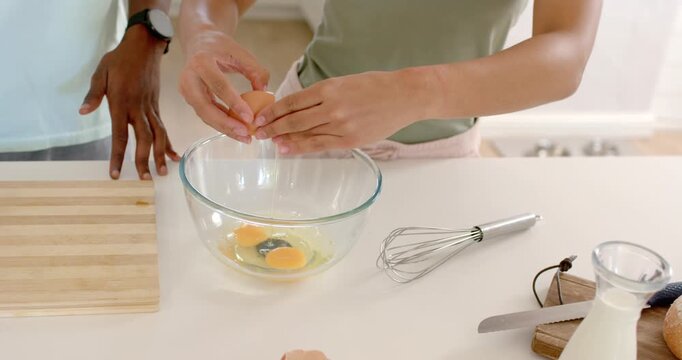 African American couple watching woman cracking eggs into bowl at counter after eggs cracked to eat