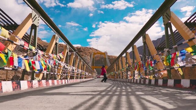 Happy and excited young woman jumping and running with joy on Chicham bridge at Spiti Valley, Himachal Pradesh, India. Tourist enjoying vacation in mountains 