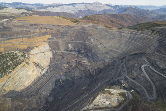 Aerial view of a massive open-pit mine with terraced rock walls and winding roads nestled among rugged mountains in Santa Lucia de Gordon, Castile and Leon, Spain.