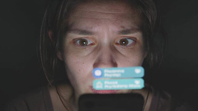 Gros plan sur le visage d&rsquo;une femme &eacute;clair&eacute; par les notifications d&rsquo;un smartphone dans l&rsquo;obscurit&eacute;, mouvements rapides des yeux et respiration anxieuse, ambiance minimaliste
