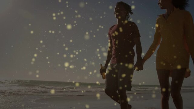 Camera starting at feet and showing couple walking handholding on shore romance sparkles overlaying