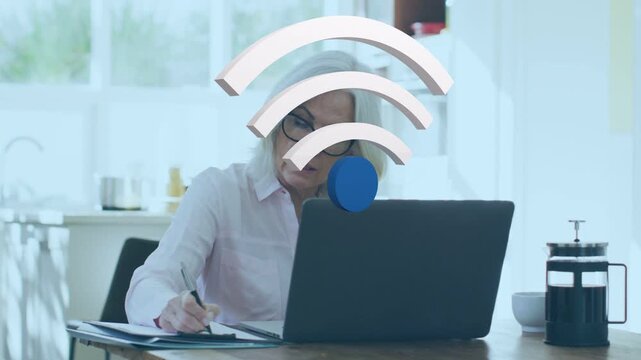 Senior woman writing at laptop in kitchen, Wi?Fi symbol appearing, signaling remote work link