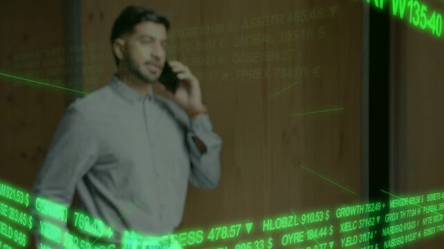 Vertical video: Green ticker driving Indian man on phone speaking while tracking stocks in office