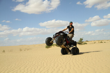 Obraz premium Young quad bike rider doing wheelie in desert